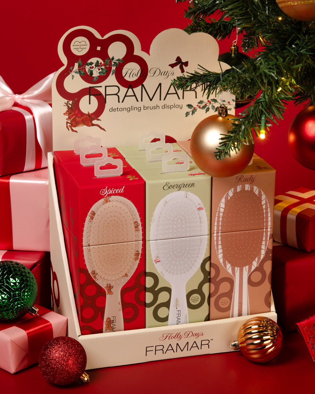 The Holly Days 9-piece detangle brush display with Spiced, Evergreen and Rudy brushes, set among red gifts and ornaments